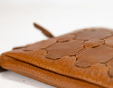 Close-up of a brown leather clutch with embossed design on a white background