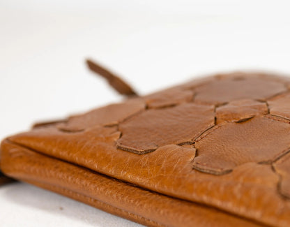 Close-up of a brown leather clutch with embossed design on a white background