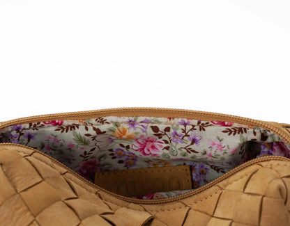 Close-up of a tan woven handbag with a floral interior lining.