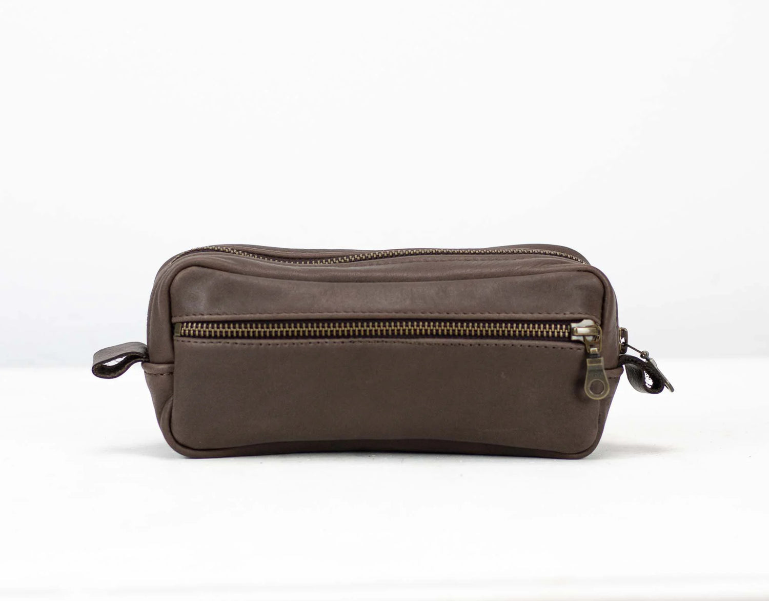 Brown leather toiletry bag with zippers on a white background