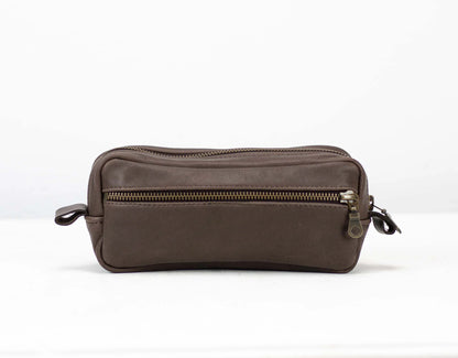 Brown leather toiletry bag with zippers on a white background