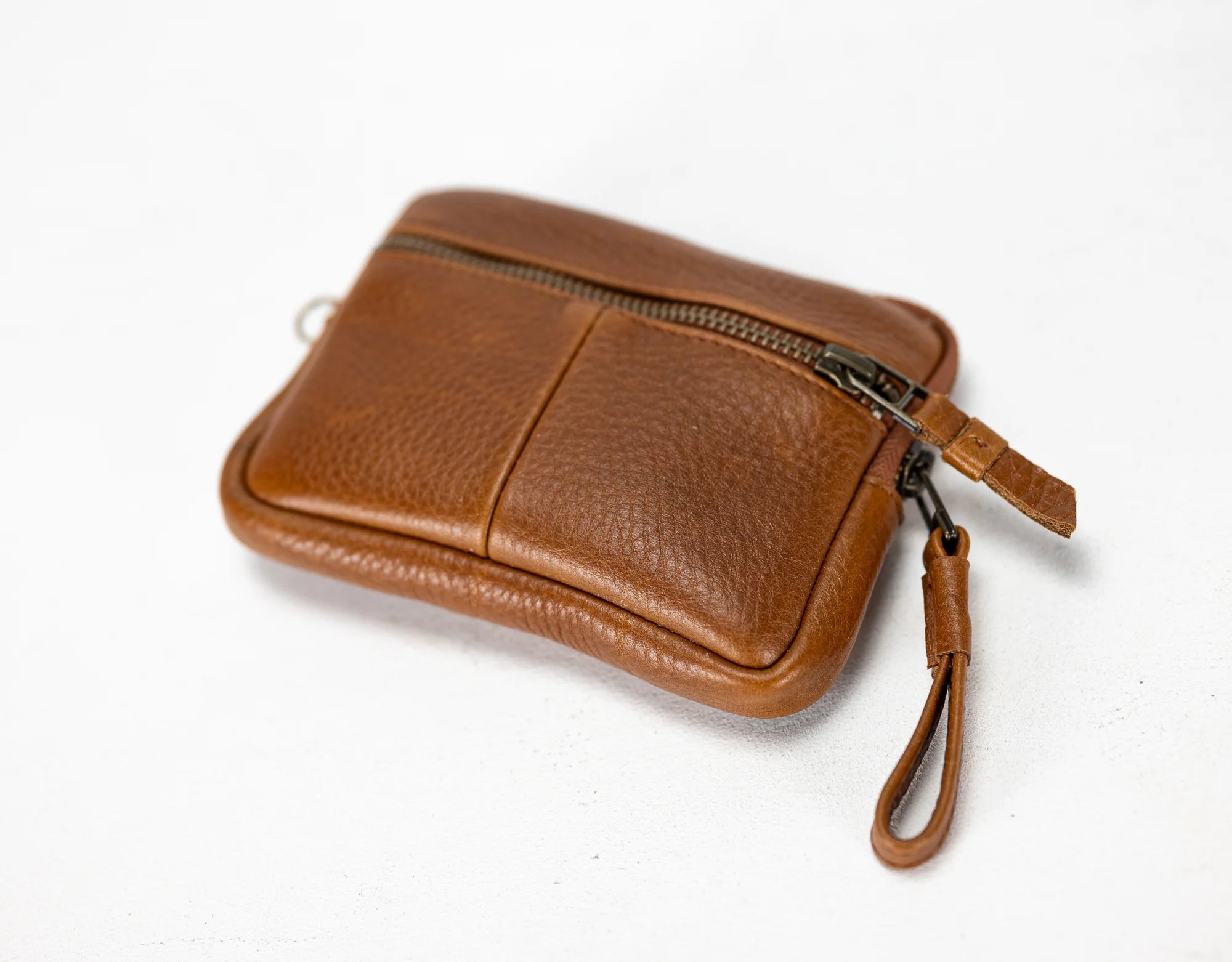 Brown leather wristlet with a zipper on a white background