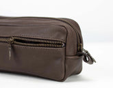 Brown leather toiletry bag with zippers on a white background