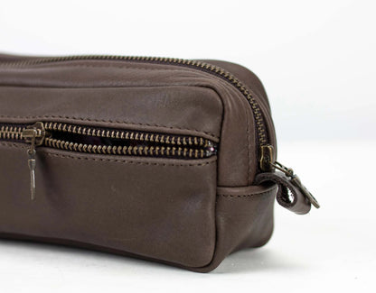 Brown leather toiletry bag with zippers on a white background