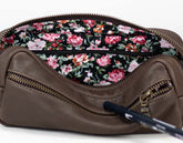 Brown leather bag with floral interior and pen on a white background