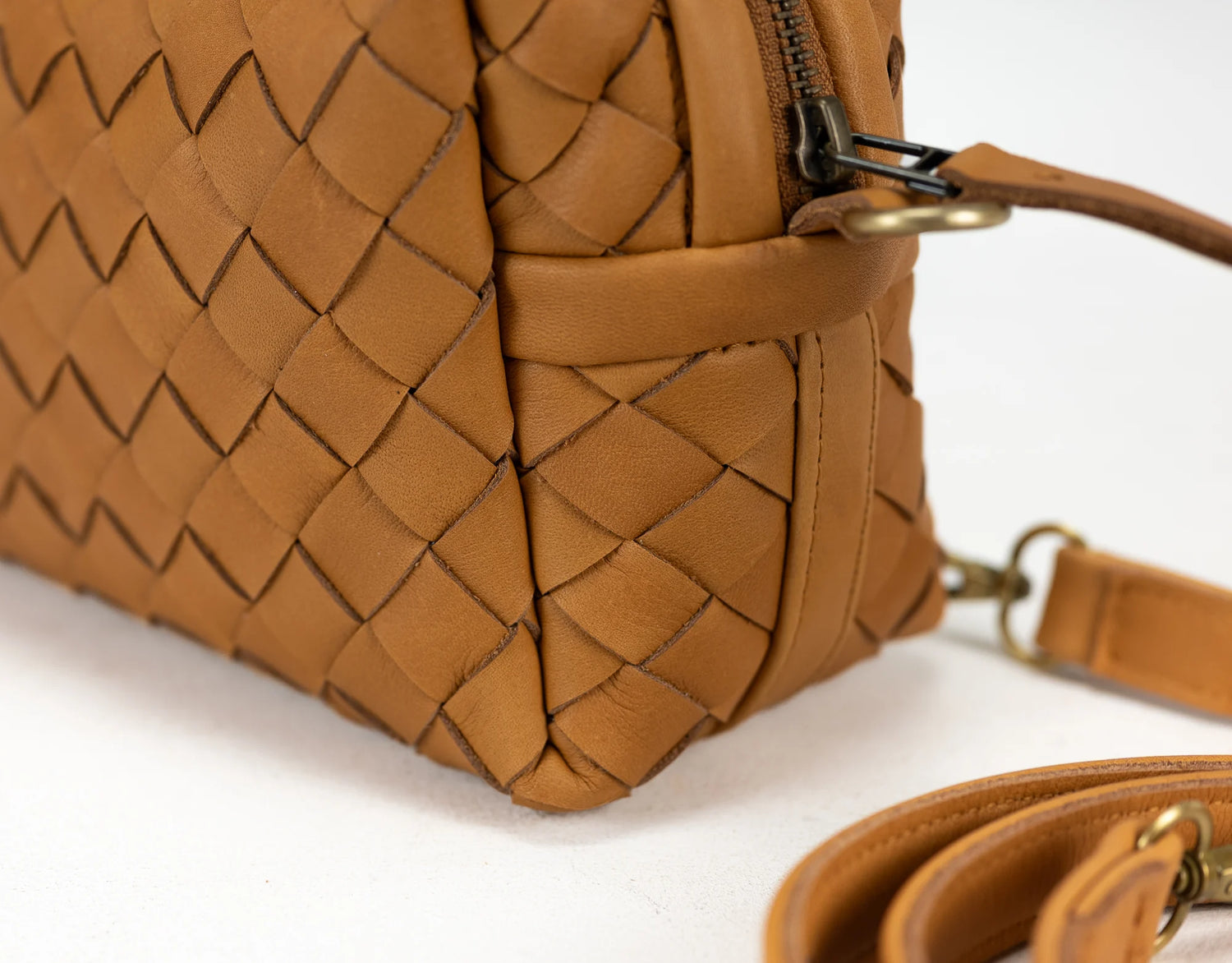 Brown woven handbag with a strap on a white background
