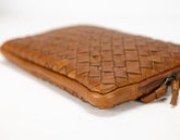 Brown woven leather clutch bag on a white background