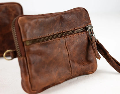 Brown leather clutch bag with a zipper on a white background