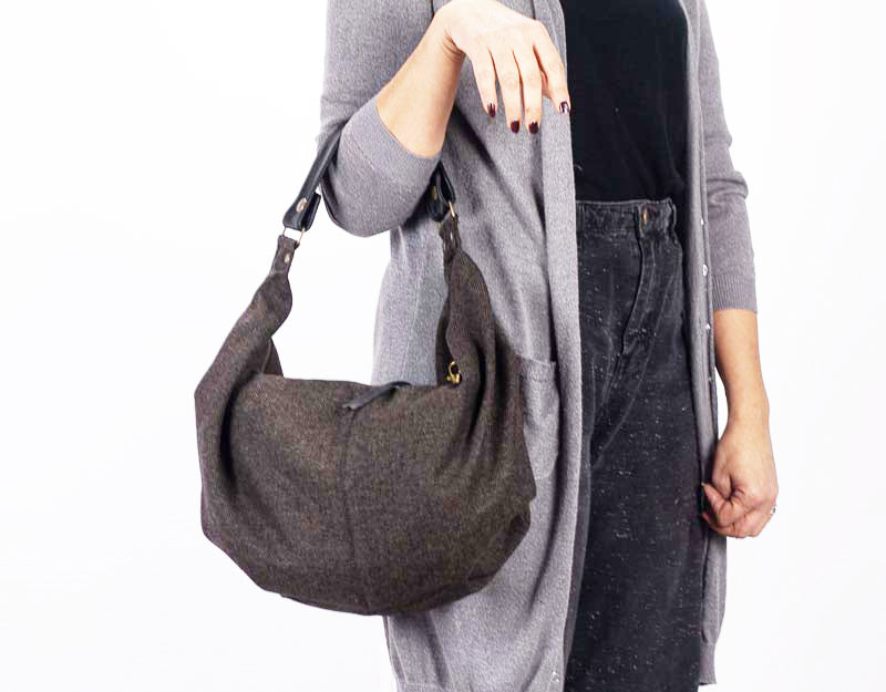 Person holding a gray textured handbag against a white background