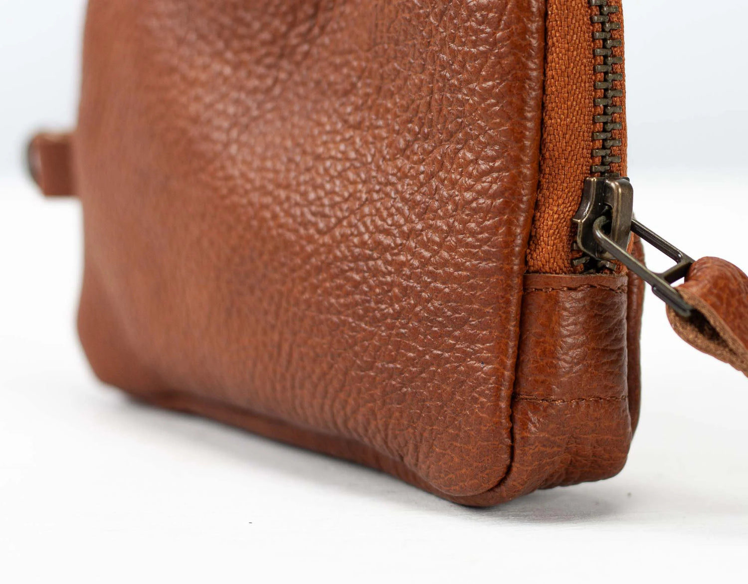 Close-up of a brown leather bag with a zipper on a white background