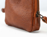 Close-up of a brown leather bag with a zipper on a white background