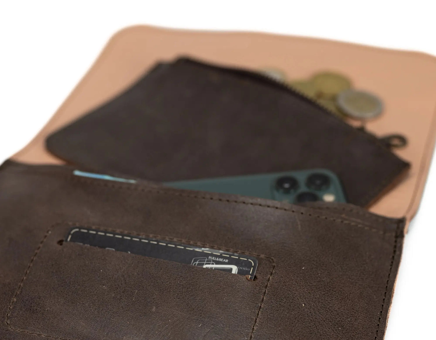 Close-up of a brown leather wallet with coins and a phone inside, on a white background.