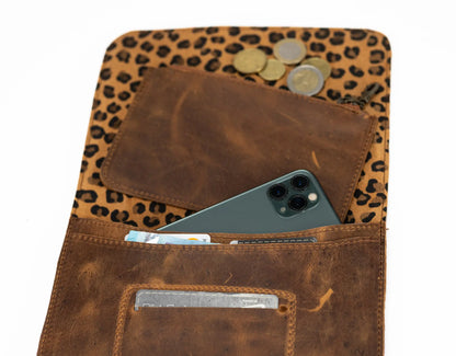 Brown leather wallet with leopard print flap, phone, coins, and cards inside on a white background