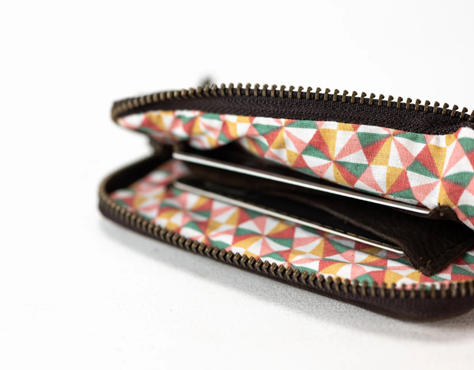 Black pouch on a beige surface with a plant and keys in the background