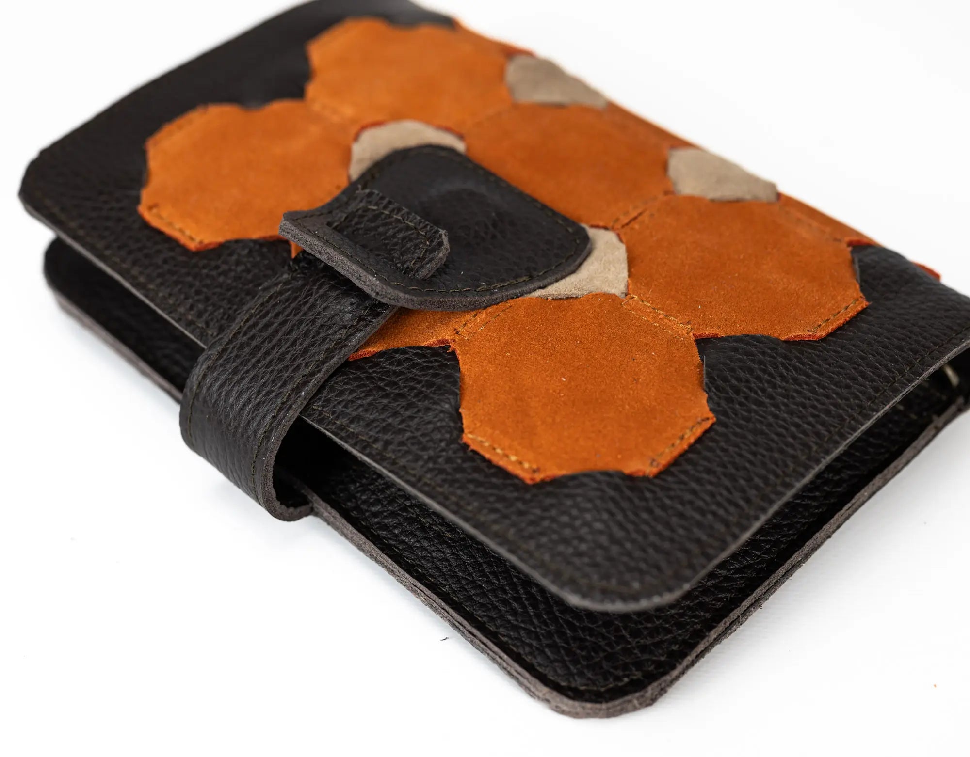 Brown leather wallet  with orange and beige hexagonal patches on a white background