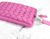 Pink woven handbag with a strap on a marble surface