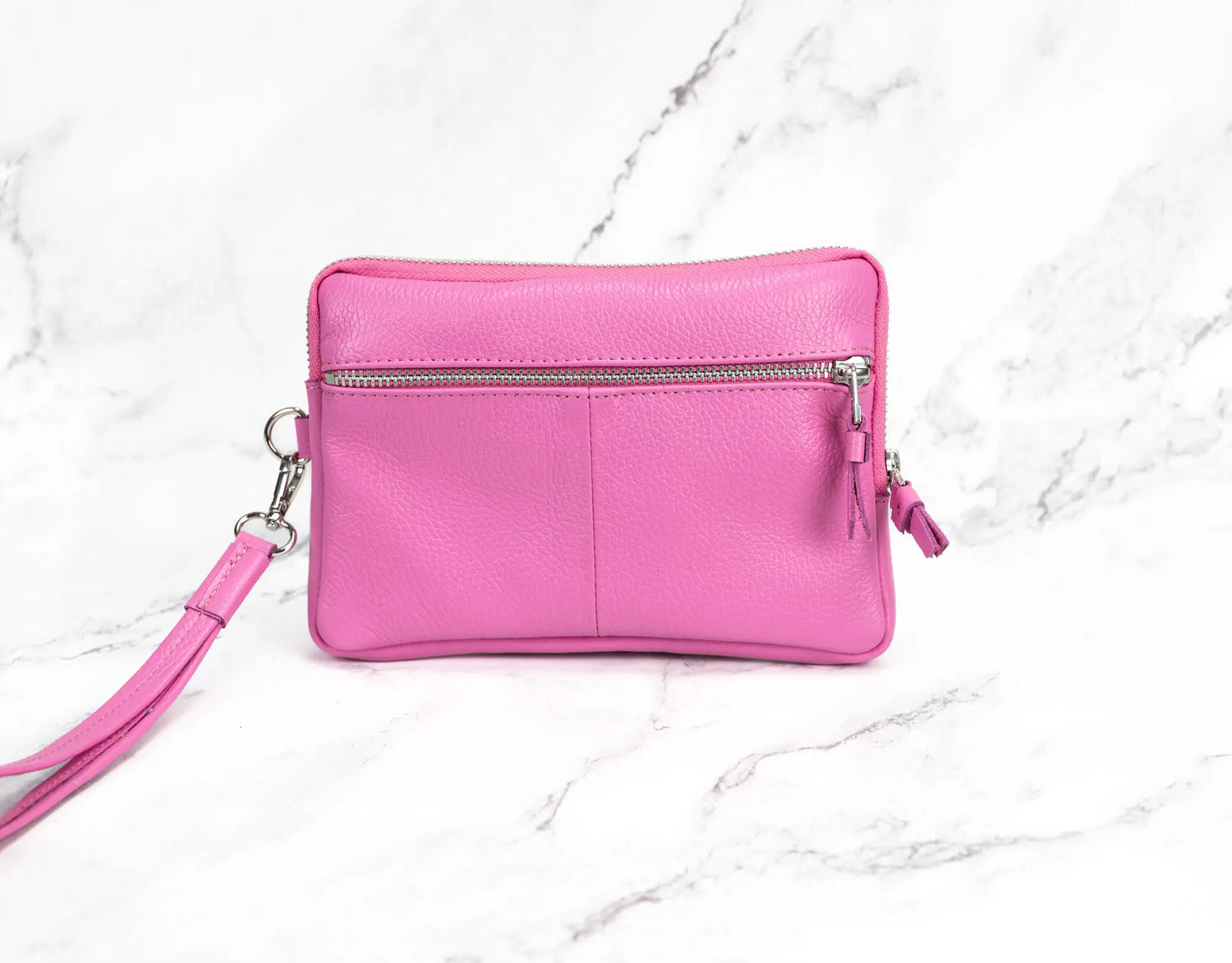 Pink wristlet purse on a white marble background