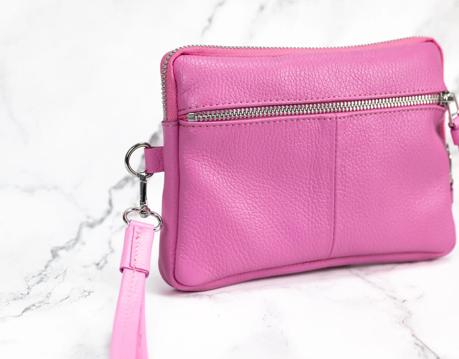 Pink leather crossbody bag on a marble surface