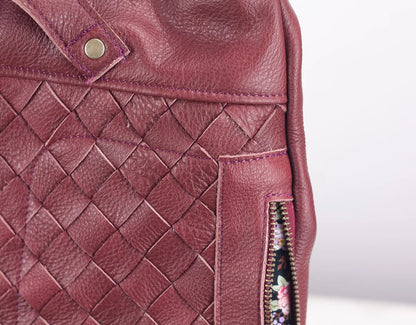 Close-up of a maroon leather bag with woven pattern and zipper detail.