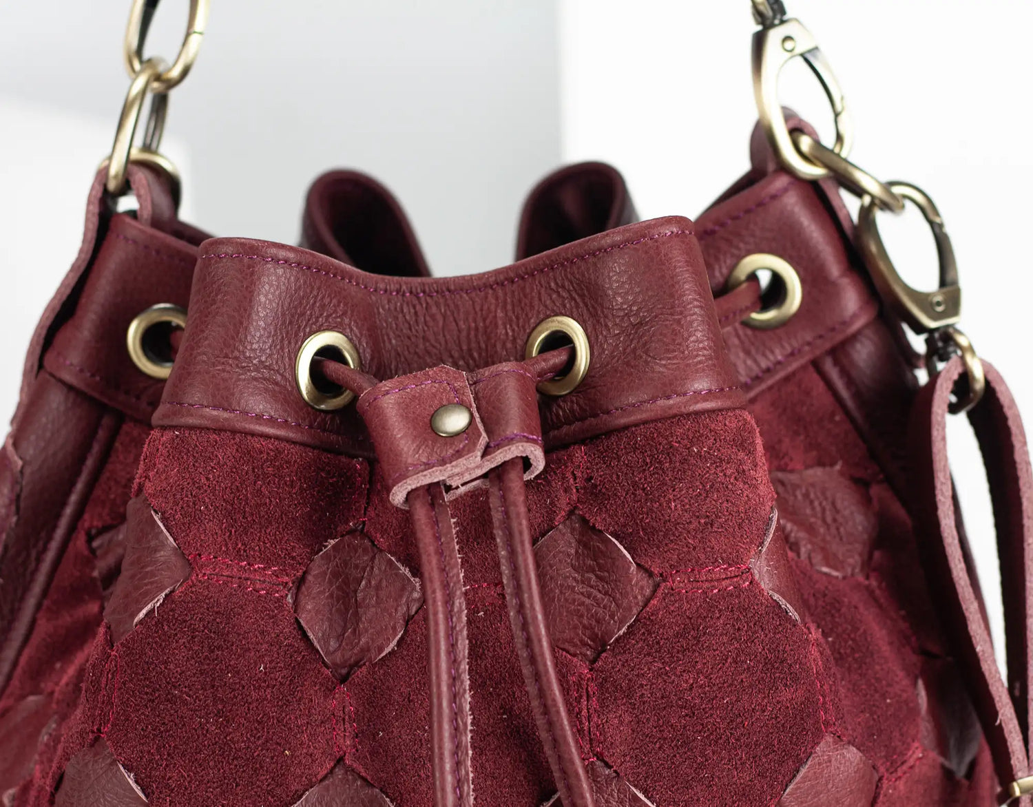 Close-up of a maroon leather handbag with gold hardware on a white background