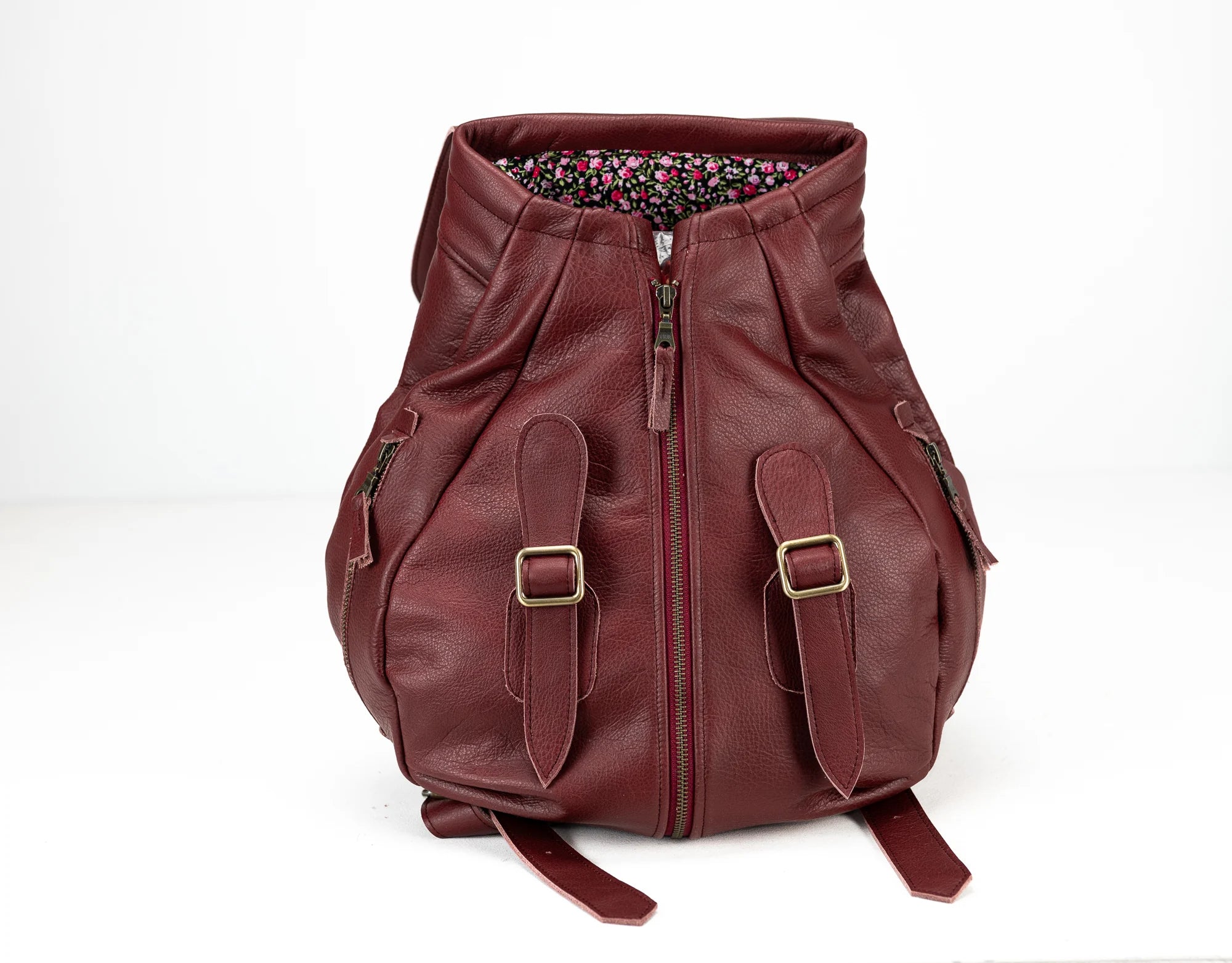Maroon leather backpack with floral lining on a white background