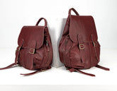 Two maroon leather backpacks on a white background