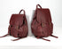 Two maroon leather backpacks on a white background