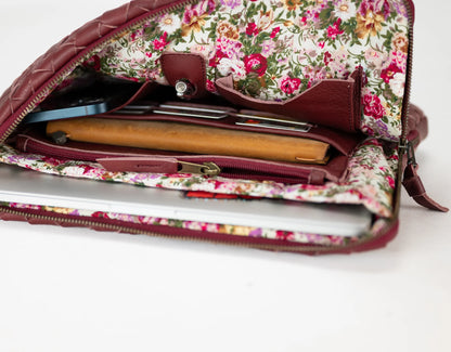 Floral-patterned clutch bag with a laptop inside on a white background