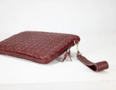 Maroon woven leather clutch bag on a white background