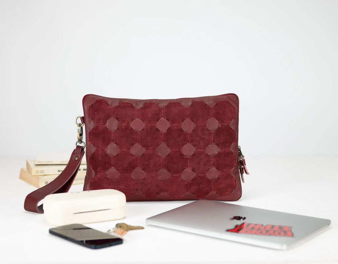 Red quilted pouch with a white surface featuring a phone, laptop, and books.