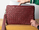 Red woven clutch bag on a wooden surface with a person&