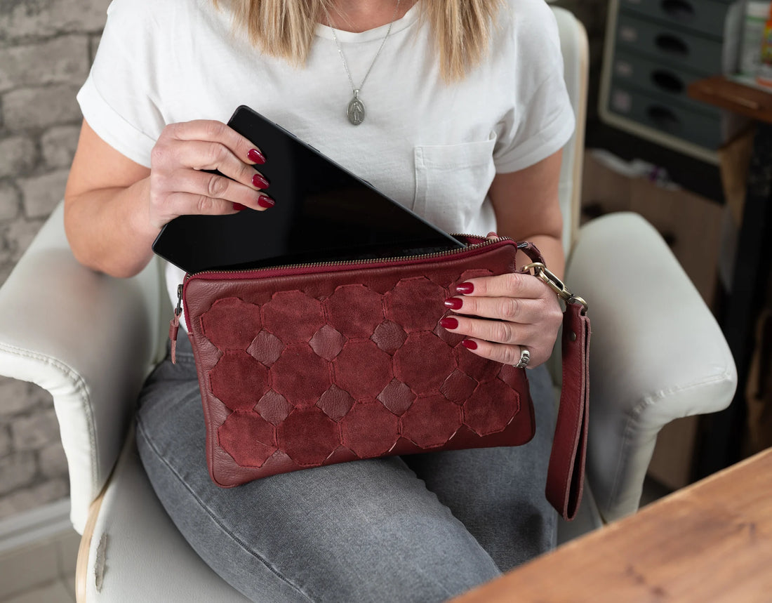 Woman sitting in a chair holding a red clutch bag with a brick wall background