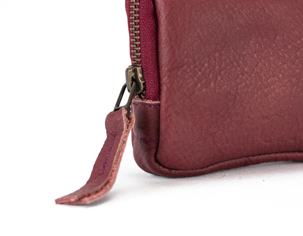 Close-up of a maroon leather pouch with a zipper on a white background#color_burgundy
