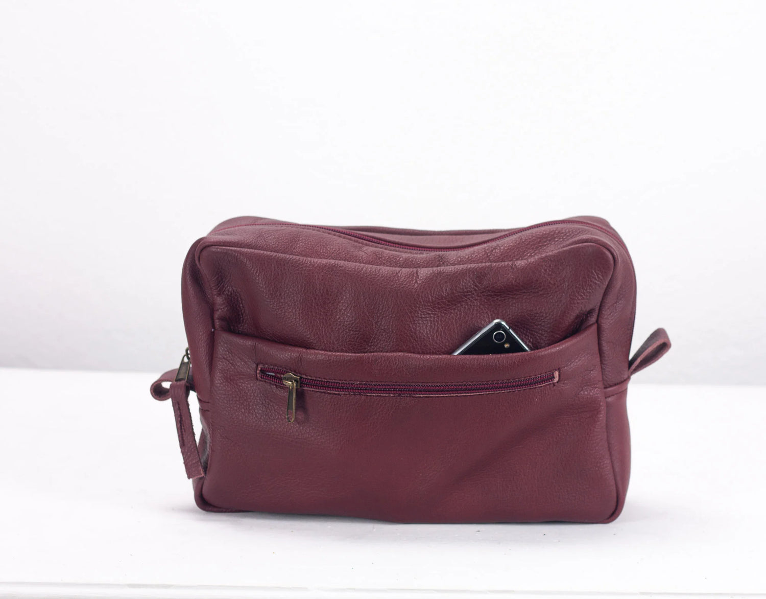 Maroon shoulder bag with a phone inside on a white background