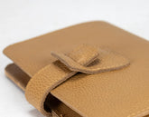 Close-up of a brown leather wallet with a strap on a white background
