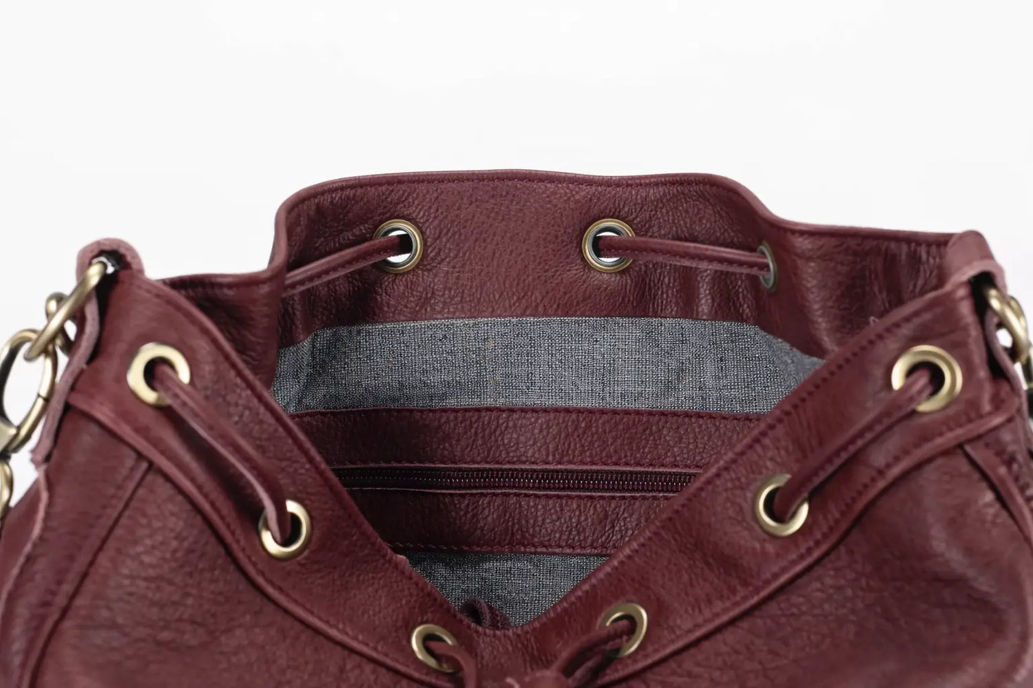 Close-up of a maroon leather bag with gold accents on a white background