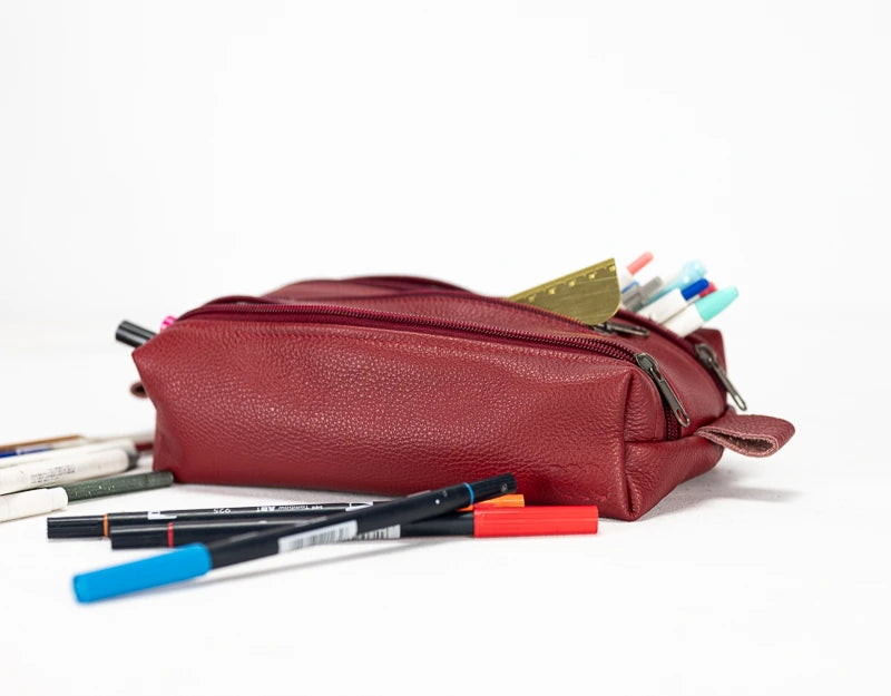 Red leather pencil case with pens spilling out#color_deep-red