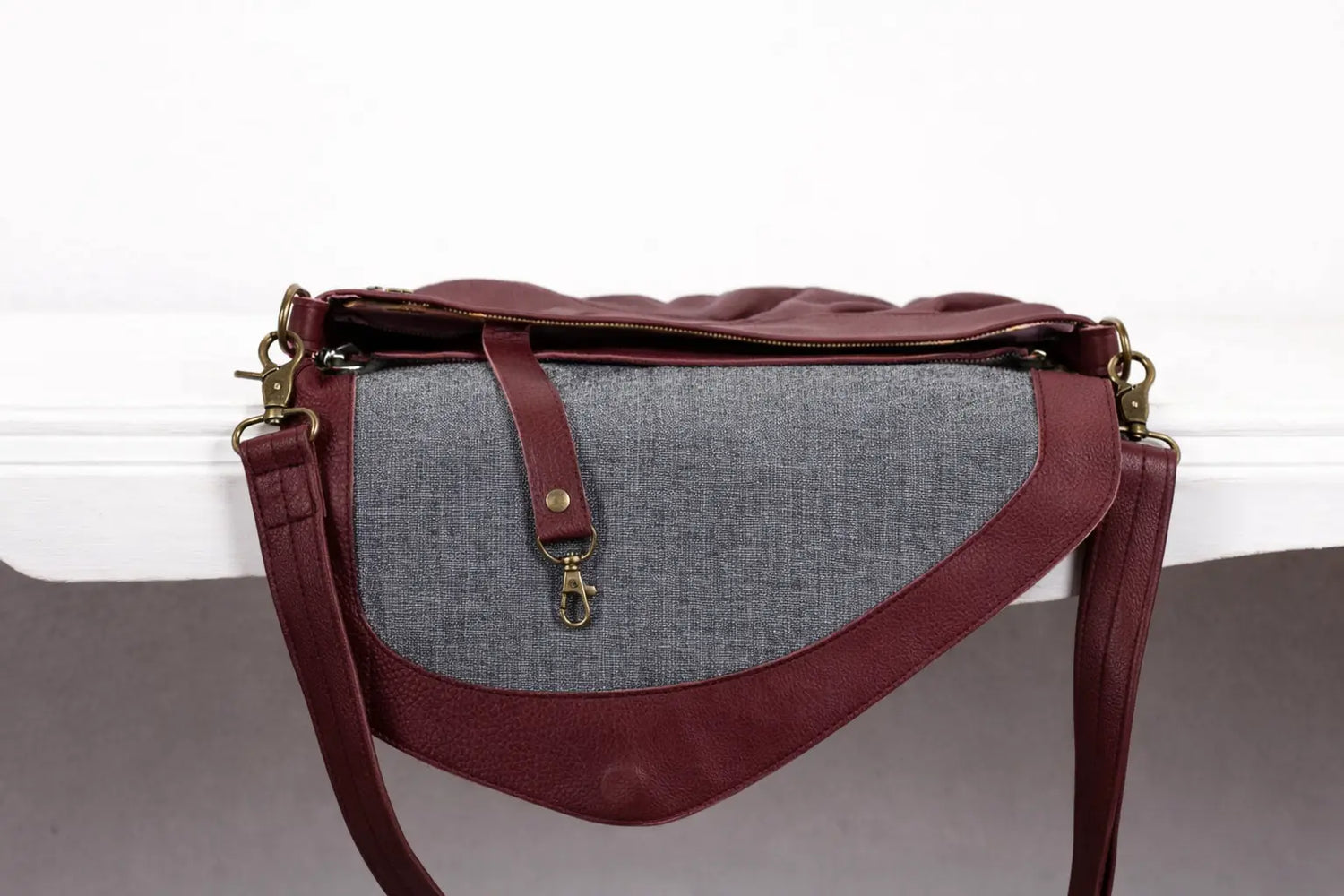 Handbag with gray fabric and burgundy leather accents on a white background