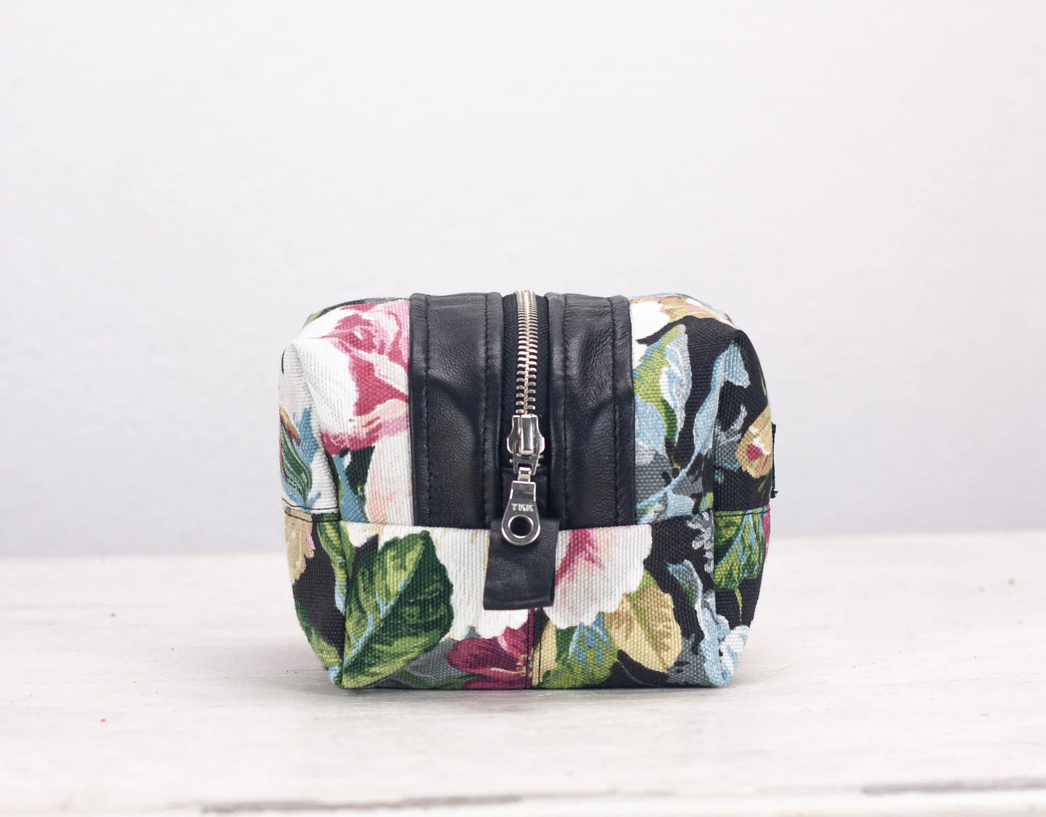 Floral-patterned pouch with a black zipper on a white background