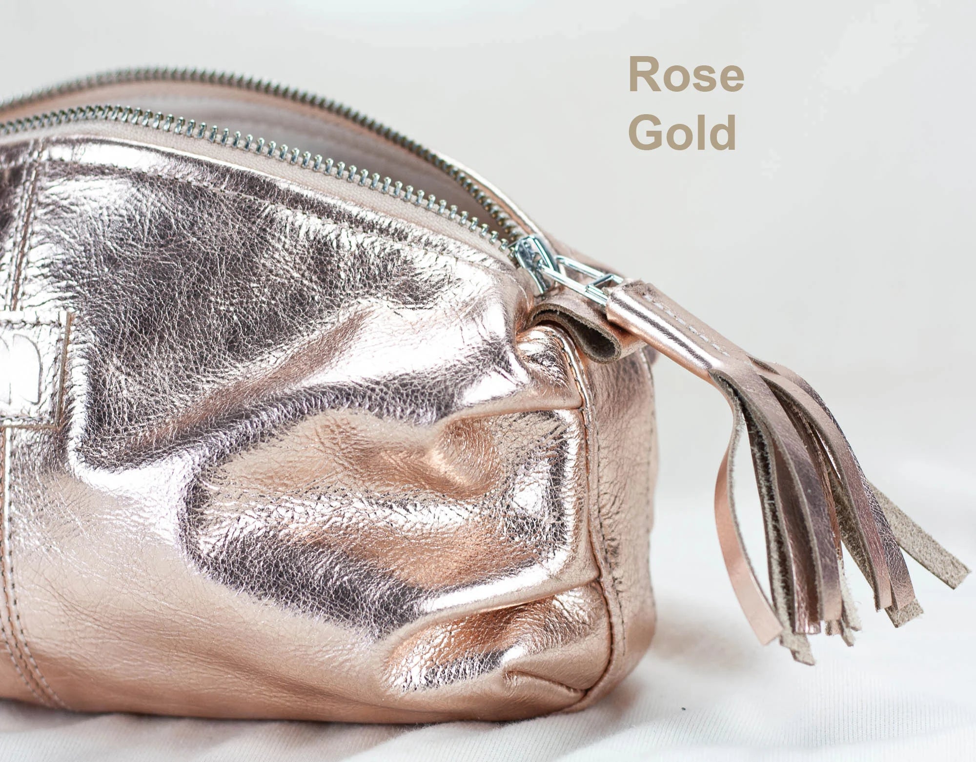 Rose gold pouch with tassel on a light background