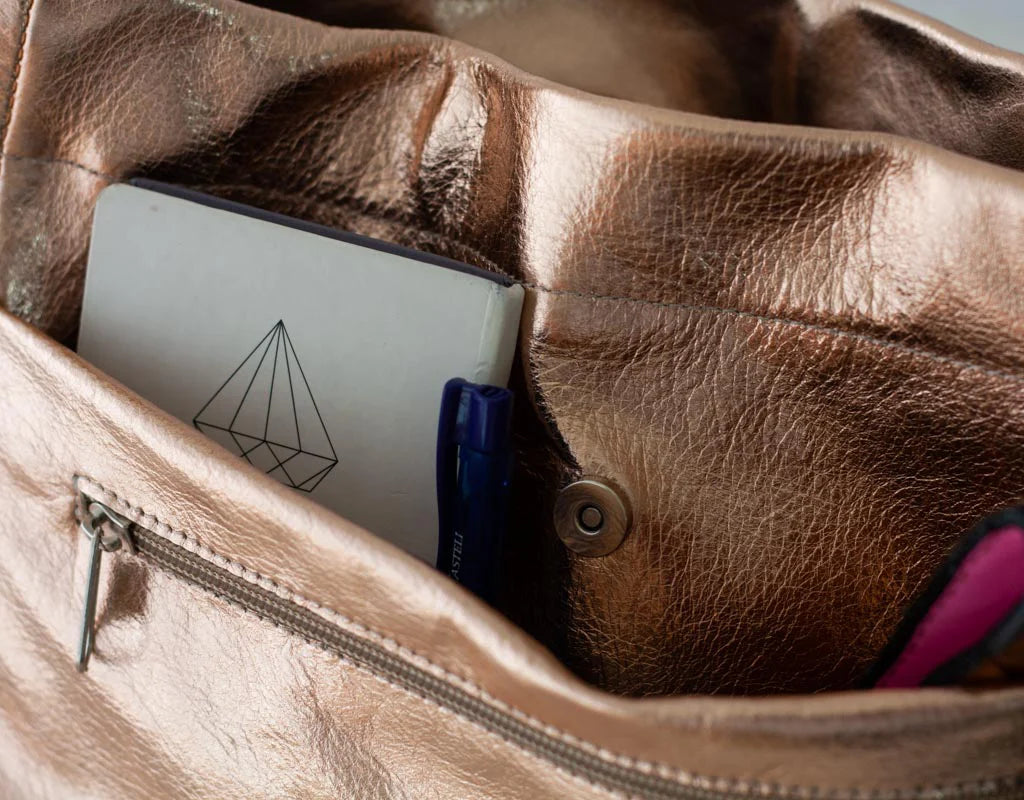 Rose gold leather bag with a notebook and pen inside