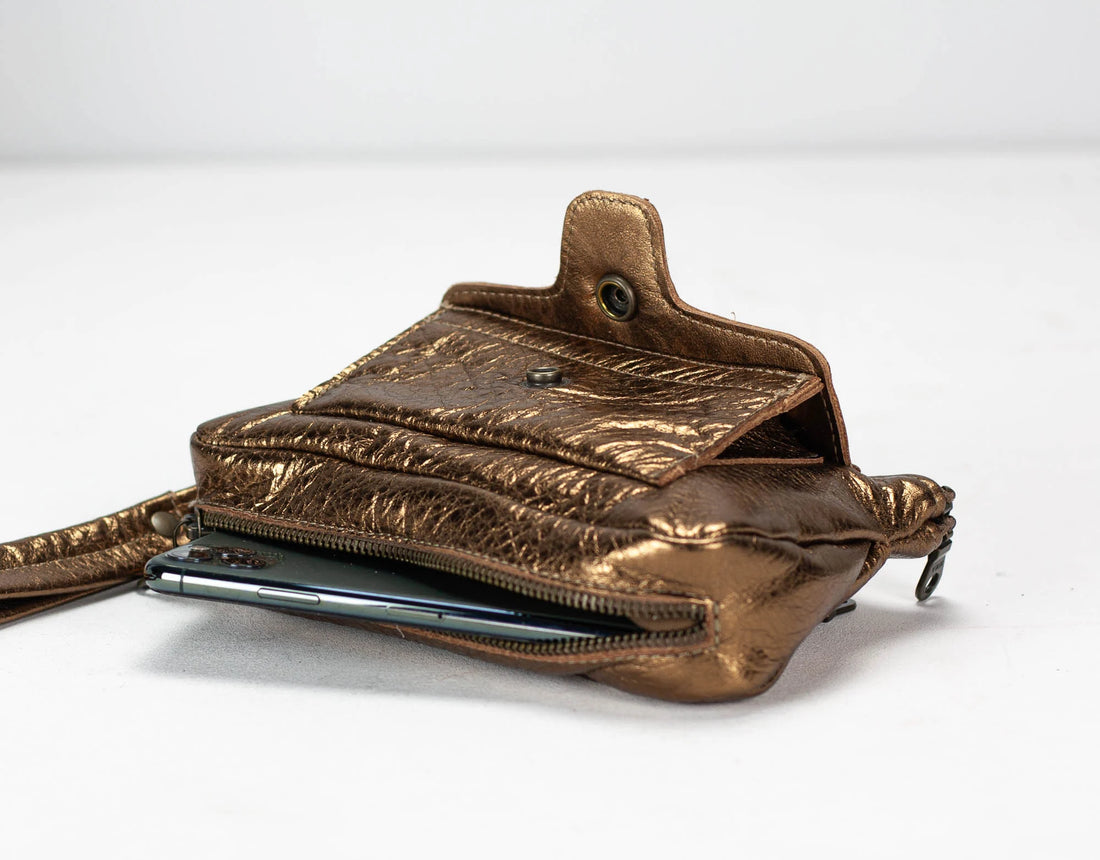 Brass leather crossbody bag with a phone case on a white background