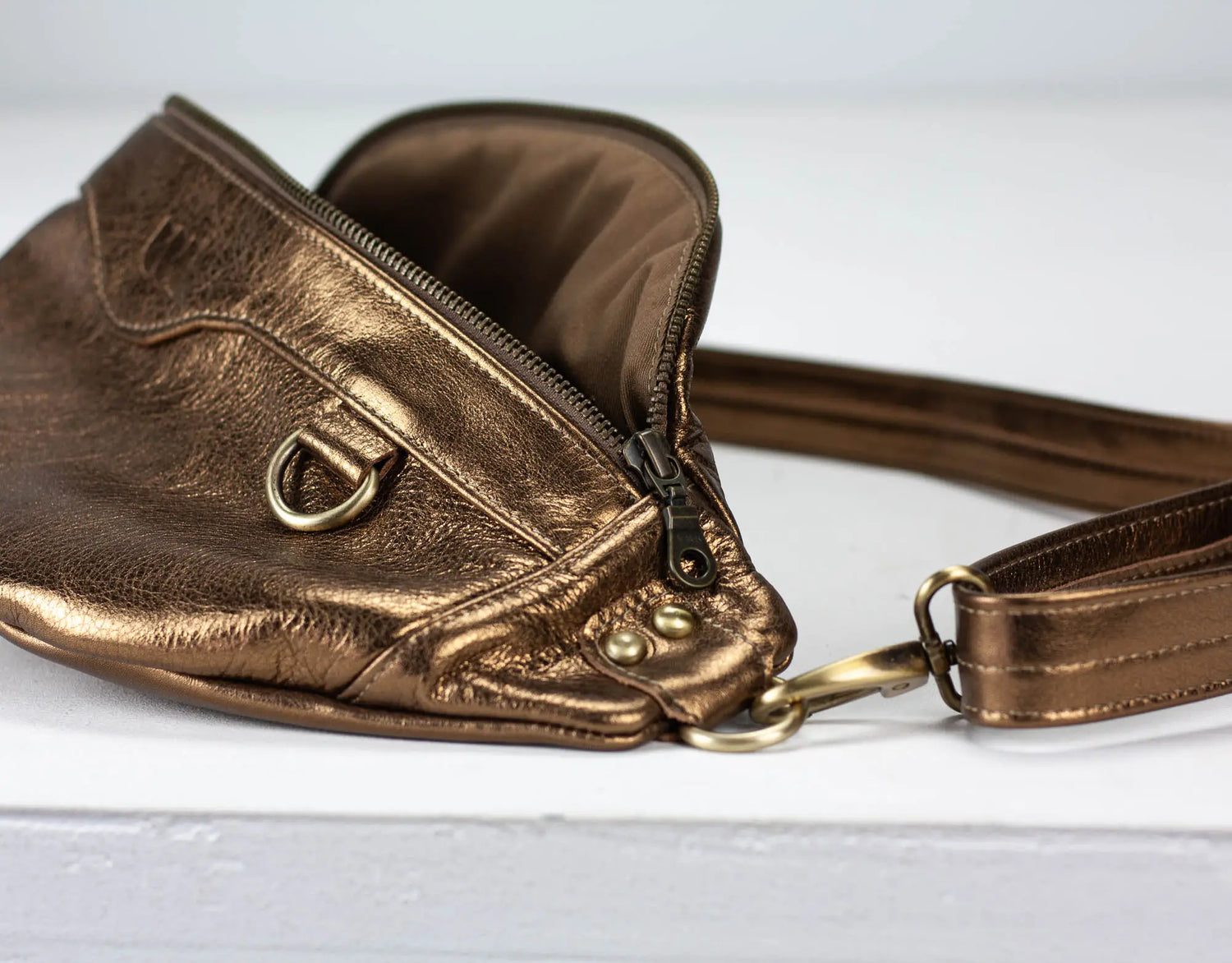 Bronze-colored leather bag with a strap on a light gray background