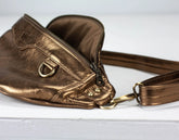 Bronze-colored leather bag with a strap on a light gray background