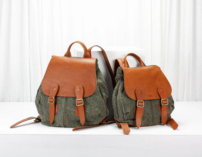 Two backpacks with green fabric and brown leather straps on a white background