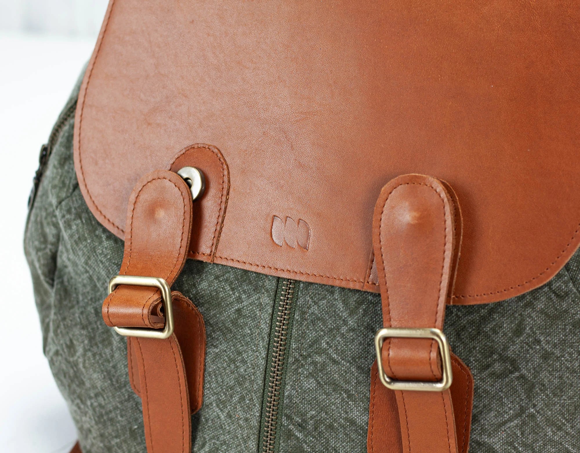Close-up of a backpack with brown leather straps and a visible brand logo.