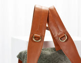 Close-up of brown leather bag straps with gold rings on a white background