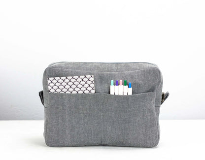 Gray fabric pouch with a pocket and markers on a white background