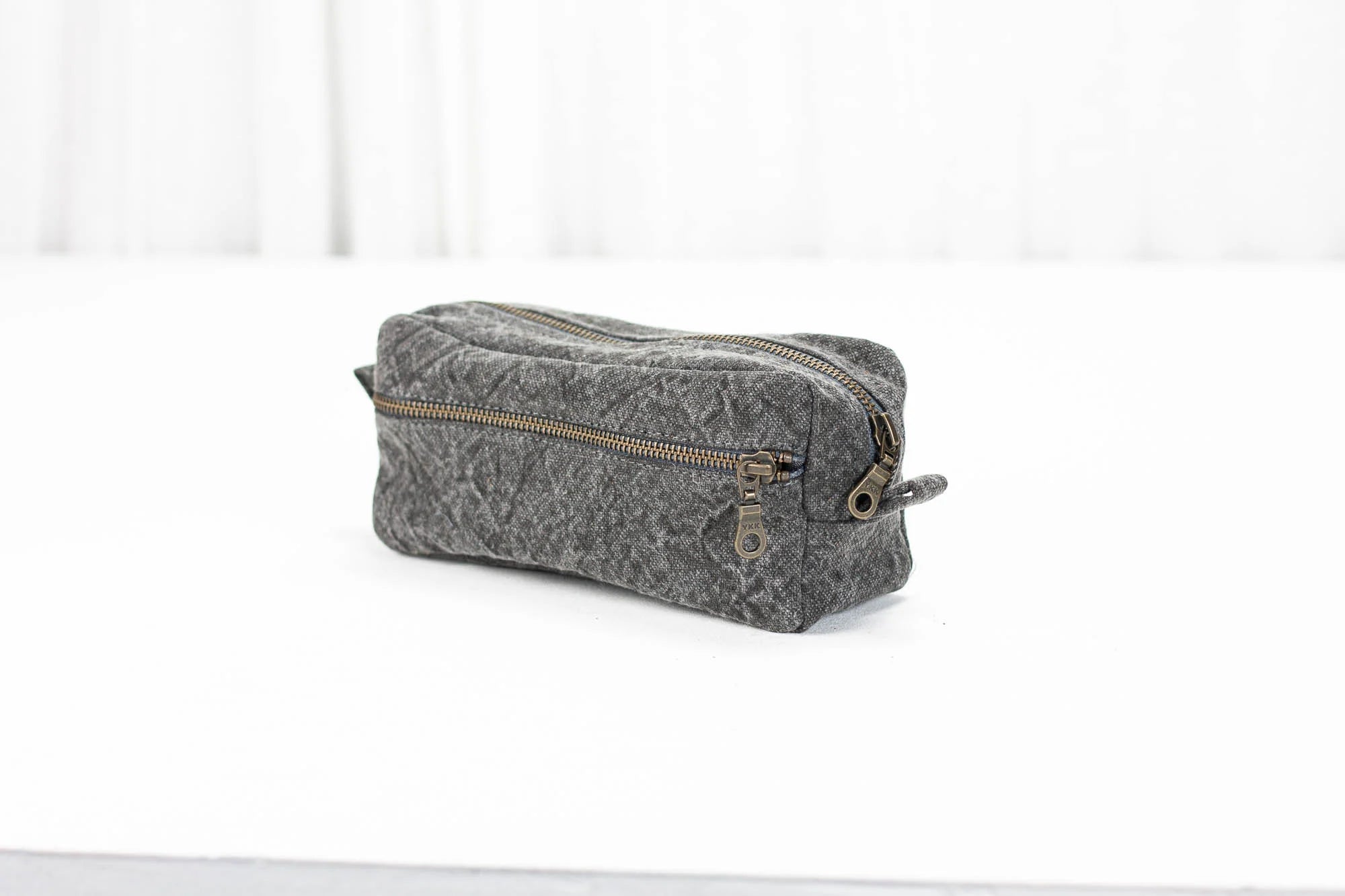 Gray cotton toiletry bag with gold zipper on a white background