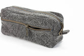 Gray textured toiletry bag with gold zipper on a white background